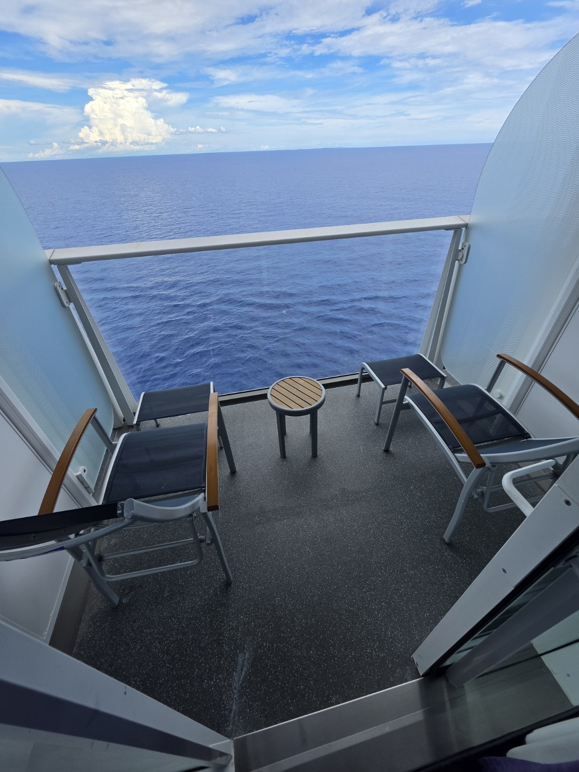 Wonder of the Seas balcony with two chairs, footrests, and a small table.