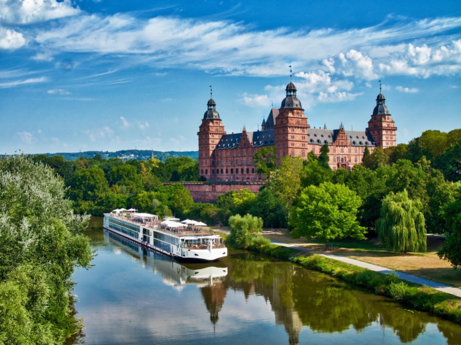 River cruise ship sailing past a historic European castle.